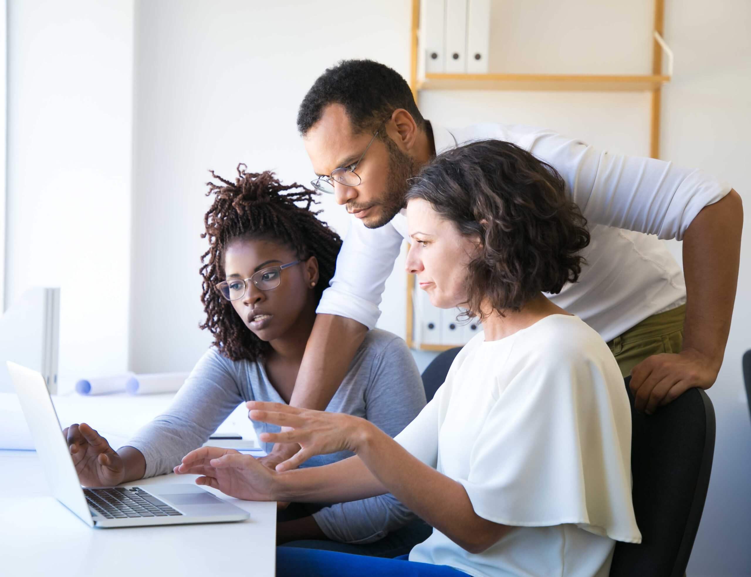 Three colleagues discussing PIPEDA and PPIPS while looking at a laptop