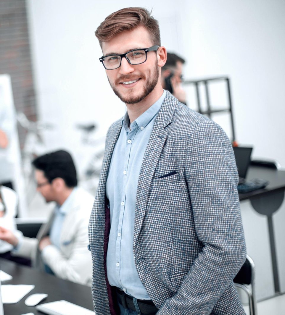 Young businessman standing in a modern office environment.